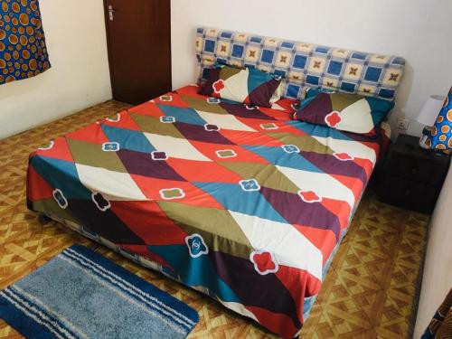阿克拉Feel At Home & be close to the Labadi Beach (5min)的床上配有色彩缤纷的被子和枕头