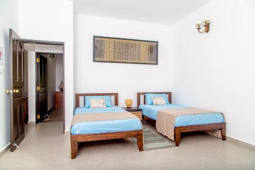 马埃岛Riverside Mount Simpson - Seychelles Island的白色墙壁客房的两张床