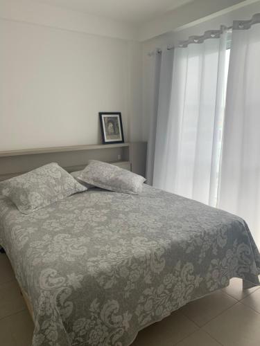 佩尼亚Apartamento em Home Club的一间卧室配有一张带毯子和窗帘的床