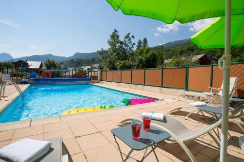 皮伊圣万桑艾格利尔酒店的一个带桌椅和遮阳伞的游泳池
