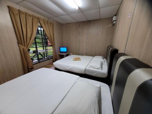 Kampong Bukit LintangHasina Resort @Sedili的小房间设有两张床和窗户