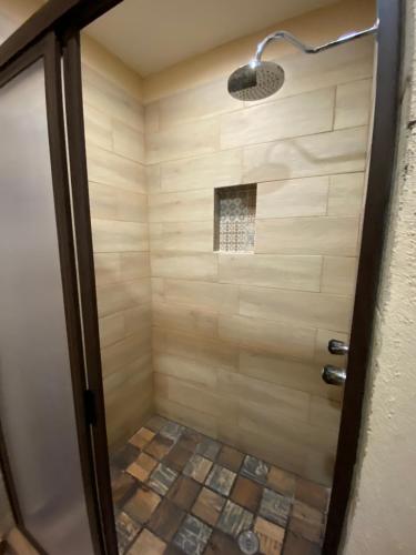 阿拉莫斯Hotel Real de los Alamos的带淋浴的浴室,铺有瓷砖地板。
