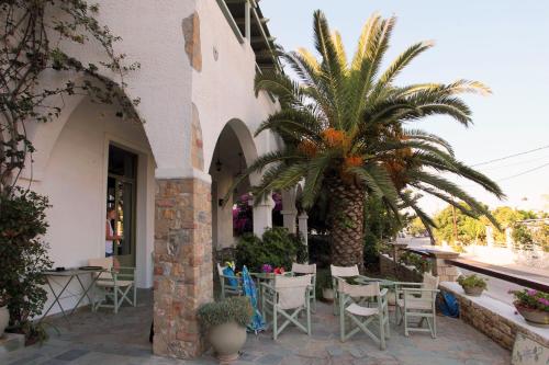 斯基罗斯岛Achilleion Hotel的一座带椅子和棕榈树的庭院,毗邻一座建筑