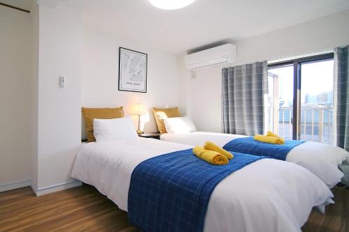东京MUMU HOUSE的两张位于酒店客房的床,上面有黄色枕头