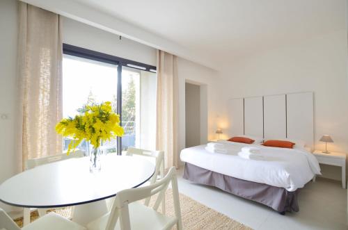 艾日La Perle d'Eze - Aparthotel的一间卧室设有两张床和一张黄色花卉桌子。