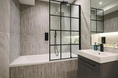 韦林花园城Portfolio Apartments - Welwyn Town Centre的带淋浴、盥洗盆和浴缸的浴室