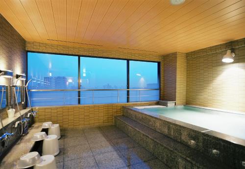 富山富山曼藤酒店的一间带大浴缸及大窗户的浴室