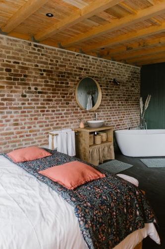 西内La cabane du potager - Ferme de Linciaux的一间卧室设有一张床和砖墙
