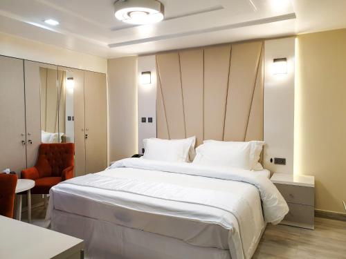 阿布贾Musada Luxury Hotels and Suites的卧室配有一张白色大床和一把椅子