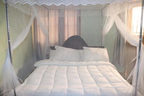金贾Jusvero Motel的卧室配有白色天蓬床和白色枕头