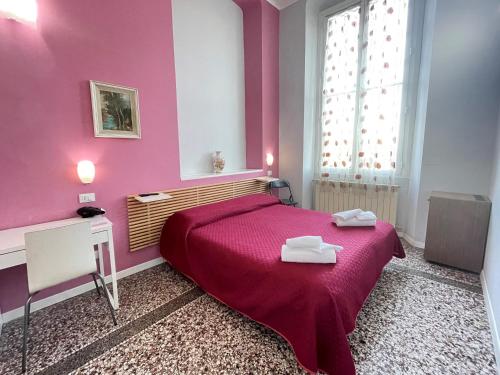 阿伦扎诺塞瑞纳酒店的粉红色的卧室,配有带两条毛巾的床