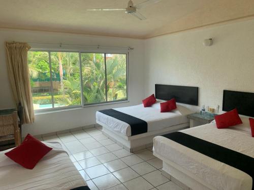 曼萨尼约Hotel Parotas Manzanillo的酒店客房设有两张床和窗户。