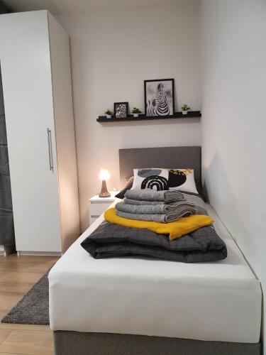 林茨Leon2的一间卧室配有白色的床和黑色和黄色的毯子