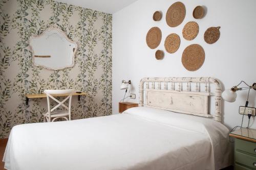 丘利利亚Hostal El Pozo的卧室配有白色的床和镜子