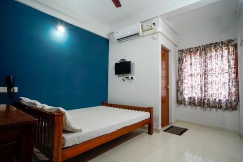 科钦Reach Residency的一间卧室设有一张床和蓝色的墙壁