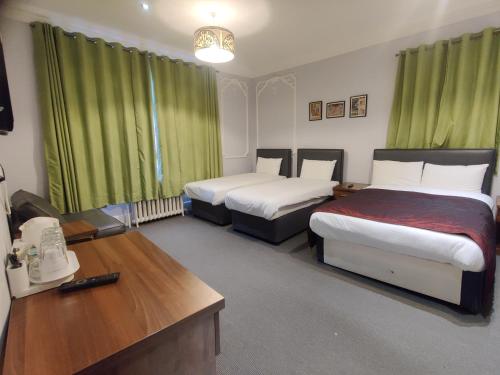 伦敦切尔西别墅住宿加早餐酒店的客房设有两张带绿窗帘的床和书桌