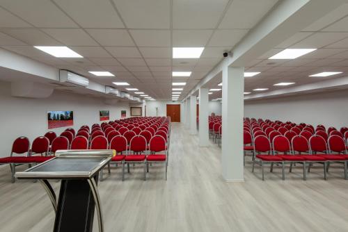豪伊杜索博斯洛Hotel Barátság的一座配有红色椅子和桌子的空的讲座大厅