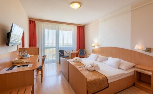 豪伊杜索博斯洛Hotel Barátság的酒店客房设有一张大床和一张书桌。