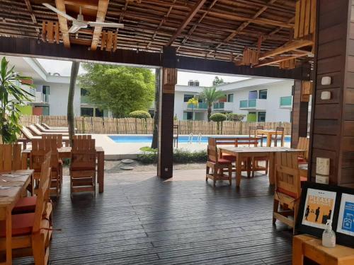 利伯维尔ONOMO Hotel Libreville的一间带木桌和椅子的餐厅以及游泳池