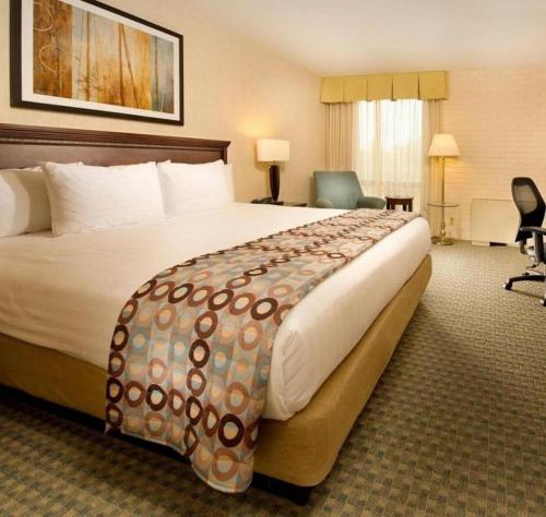 堪萨斯城Hotel Lotus Kansas City Stadium的酒店客房带一张大床和一把椅子
