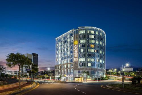 西归浦市Shin Shin Hotel Jeju Worldcup的一座高大的玻璃建筑,上面有时钟