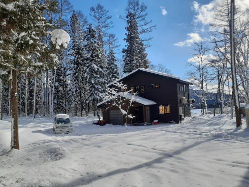 白马村Hakuba Kaede House的雪地小屋前面有一辆面包车