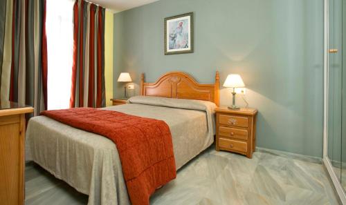 卡拉德米哈斯奥纳康帕纳里欧公寓式酒店的一间卧室配有一张带红色毯子的床