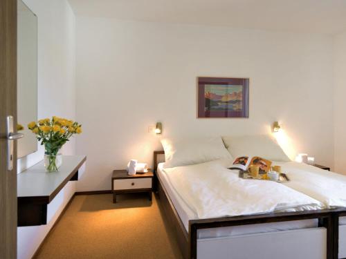 圣莫里茨偶瓦四圣莫里茨 - 巴德公寓的一间卧室,配有一张床和花瓶