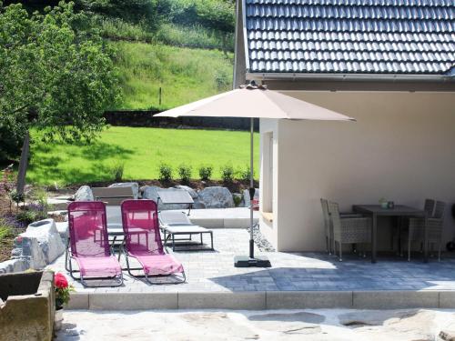 HofstettenHoliday Home am Bächle by Interhome的庭院配有2把粉红色的椅子和遮阳伞