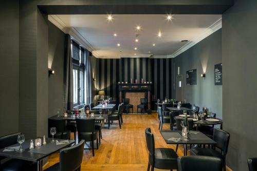 列日乐凯恩银D酒店的餐厅设有黑色桌椅和壁炉