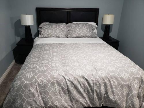 卡尔加里Cozy Two Bedroom Guest Suite in NW的一张带白色床罩和两盏灯的大床