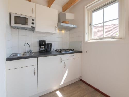 韦默尔丁厄Holiday Home Zeeuwse Cottage Wemeldinge-3 by Interhome的厨房配有白色橱柜、水槽和窗户。