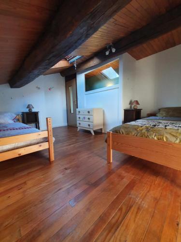 米尔库尔Gite des luthiers的一间卧室设有两张床,铺有木地板