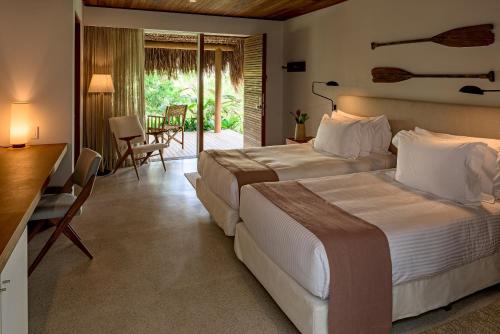 托兰克索Hotel Fasano Trancoso的酒店客房带两张床、一张桌子和椅子。