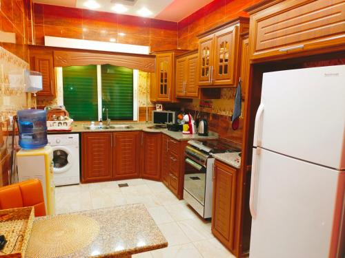 马达巴Maria Home的厨房配有木制橱柜和白色冰箱。
