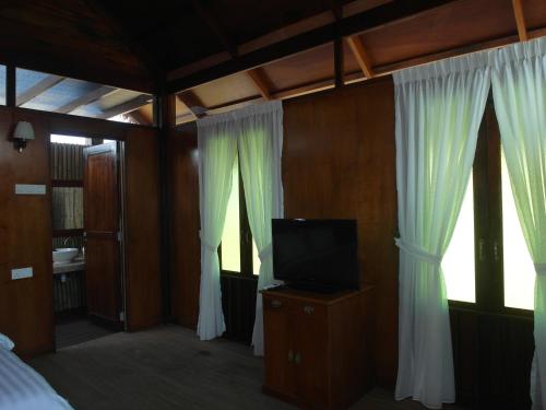 珍南海滩格马来村旅馆的一间卧室配有床、电视和窗帘