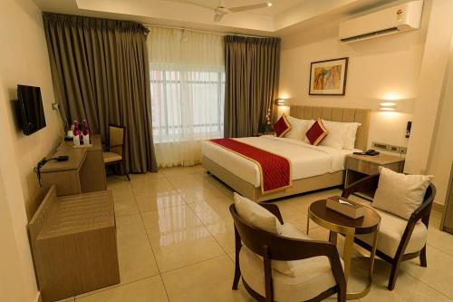 AttingalSoorya的酒店客房带一张床、一张桌子和椅子