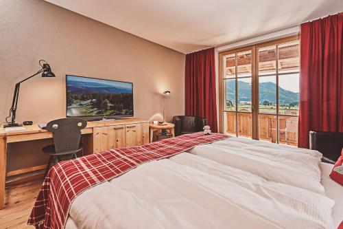 格拉绍Das Achental Resort的一间卧室配有一张床、一张书桌和一台电视