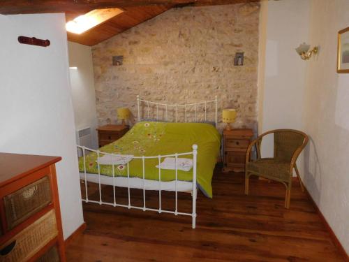 LimalongesChatenet self catering stone House for 2 South West France的一间卧室配有一张带绿色棉被和椅子的床