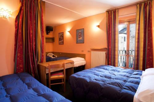 利莫内皮埃蒙特Hotel La Piazzetta的一间卧室配有蓝色的床、书桌和窗户。