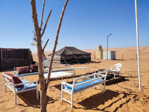 Al WāşilBidiya Dunes camp عزبة بدية ديونز的沙漠中的帐篷和椅子