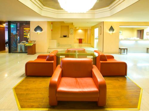 滨松滨松埃斯特酒店的大堂设有3把橙色椅子和玻璃桌