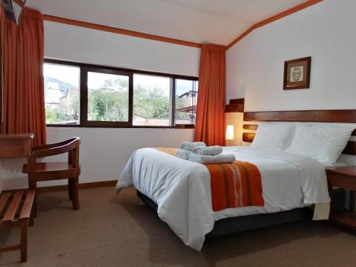 查查波亚斯Explorer Deluxe Hotel的一间卧室配有一张床、一把椅子和窗户。