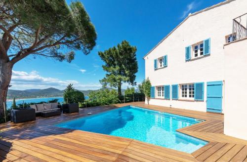圣特罗佩Villa with Magic view of Bay of Saint Tropez的一个带木甲板和房子的游泳池