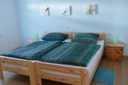 巴特拉斯费Ferienwohnung Am Sonnenhang Blecher的卧室里一张大木床,配有两个绿色枕头