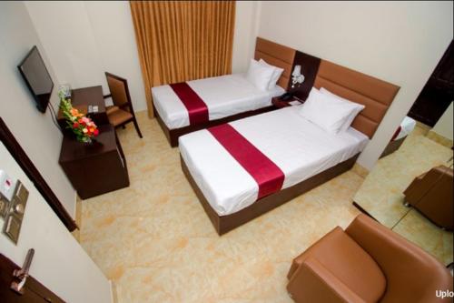 达卡Hotel Gulshan Lake View的一间设有两张床、一台电视的房间和一间房间