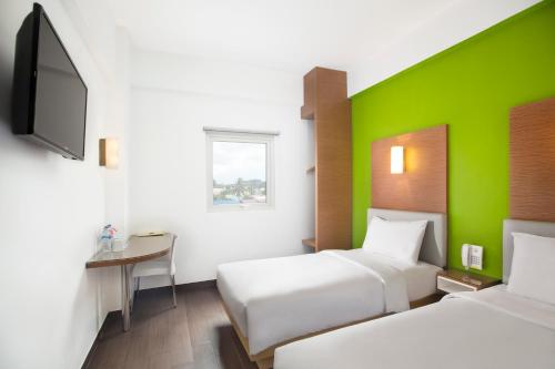 沙马林达爱玛瑞丝三马林达酒店的酒店客房设有两张床和绿色的墙壁。
