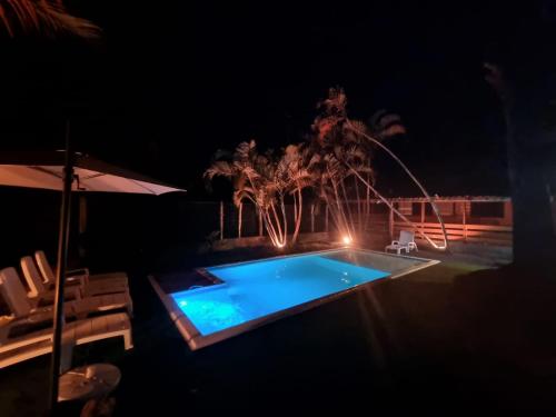 蜜岛Bossa Beach House的夜间游泳池,配有遮阳伞和椅子