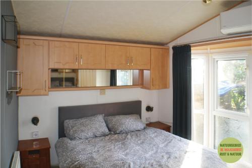 泽兰省Chalet/Caravan Camping Resort Heische Tip Zeeland的一间卧室设有一张床、木制橱柜和窗户。