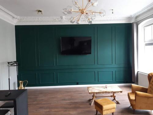 比得哥什Kamienica Bydgoska的客厅设有绿色墙壁和电视。